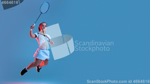 Image of Beautiful dwarf woman practicing in badminton isolated on blue background in neon light