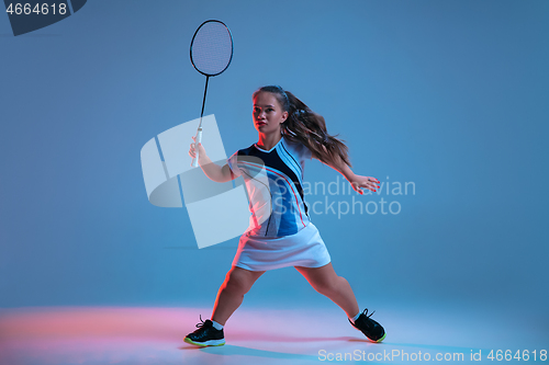 Image of Beautiful dwarf woman practicing in badminton isolated on blue background in neon light