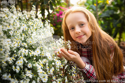 Image of Happy little girl with flowers in a garden outdoors