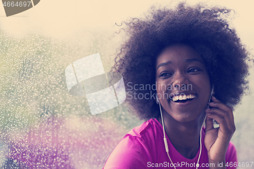 Image of portrait of young afro american woman in gym while listening mus