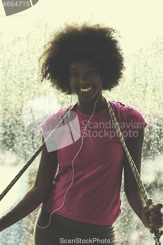 Image of portrait of young afro american woman in gym while listening mus