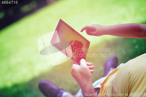 Image of grandfather and child in park using tablet