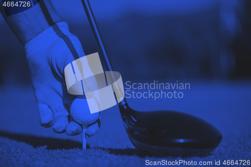 Image of golf player placing ball on tee