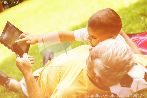 Image of grandfather and child in park using tablet