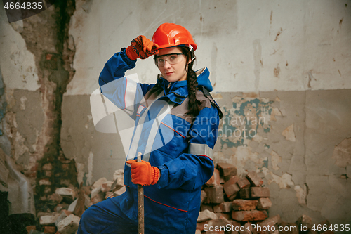 Image of Woman wearing helmet using male work tools