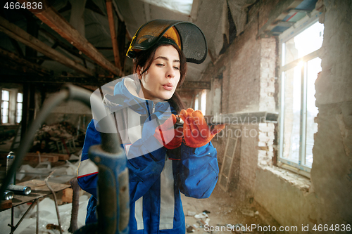 Image of Woman wearing helmet using male work tools