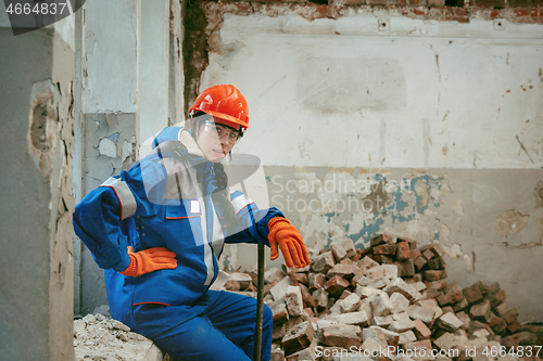 Image of Woman wearing helmet using male work tools