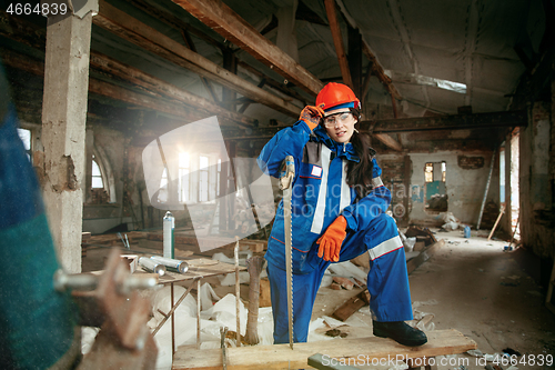 Image of Woman wearing helmet using male work tools