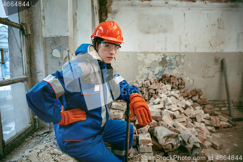 Image of Woman wearing helmet using male work tools