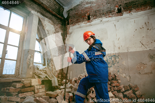 Image of Woman wearing helmet using male work tools