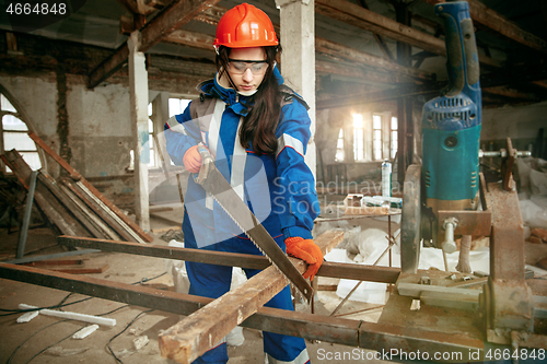 Image of Woman wearing helmet using male work tools