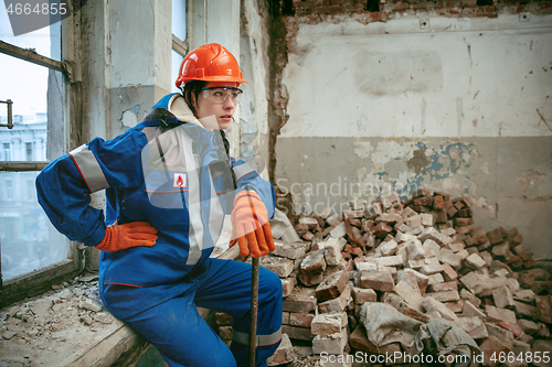 Image of Woman wearing helmet using male work tools
