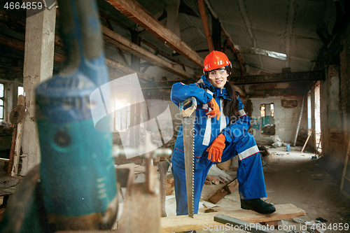 Image of Woman wearing helmet using male work tools