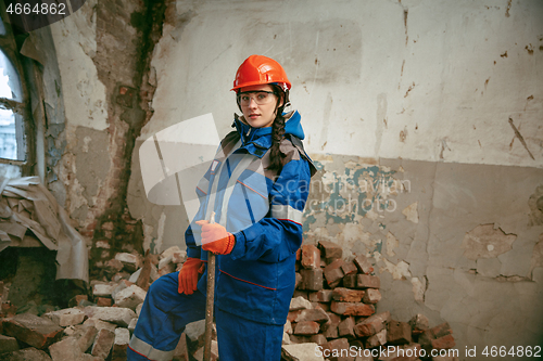 Image of Woman wearing helmet using male work tools