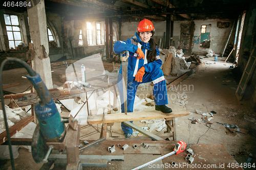 Image of Woman wearing helmet using male work tools