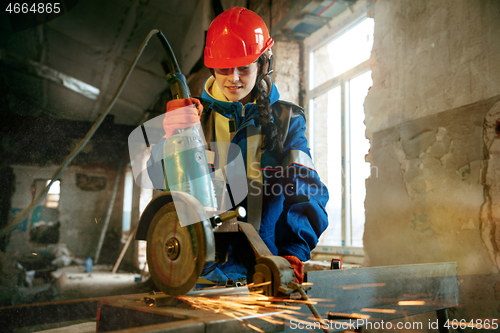 Image of Woman wearing helmet using male work tools