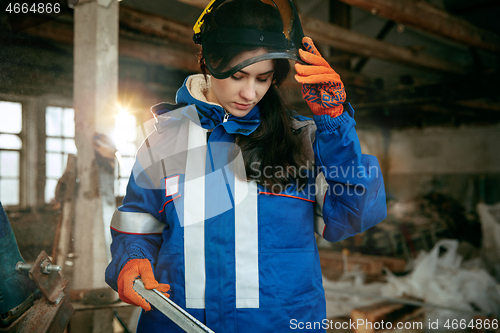 Image of Woman wearing helmet using male work tools