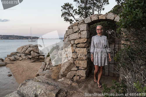 Image of Beautiful woman in luxury summer dress enjoying peaceful seascape of Porto Rafael bay at Mediterranean sea of Costa Smeralda, Sardinia, Italy at dusk