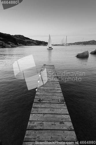 Image of Wooden pier and sailboats sailing in evening calm sea of marvellous Porto Rafael, Costa Smeralda, Sardinia, Italy. Symbol for relaxation, wealth, leisure activity