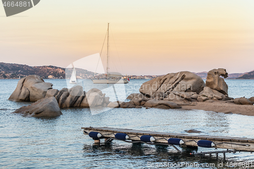 Image of Sailboat sailing by beautiful rocky formations on the Spiaggia di Punta Nera beach. Luxury summer adventure, active vacation in Mediterranean sea, Costa Smeralda, Sardinia, Italy