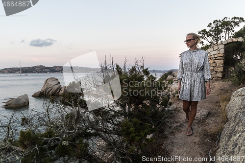 Image of Beautiful woman in luxury summer dress enjoying peaceful seascape of Porto Rafael bay at Mediterranean sea of Costa Smeralda, Sardinia, Italy at dusk