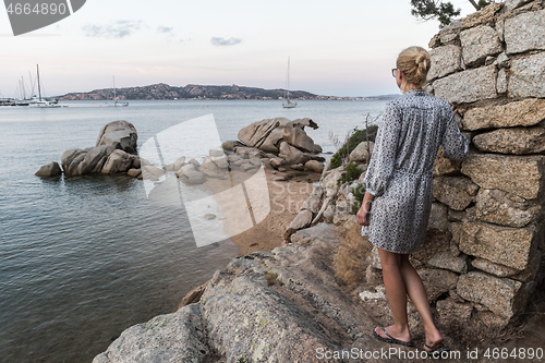 Image of Beautiful woman in luxury summer dress enjoying peaceful seascape of Porto Rafael bay at Mediterranean sea of Costa Smeralda, Sardinia, Italy at dusk