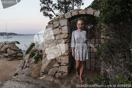 Image of Beautiful woman in luxury summer dress enjoying peaceful seascape of Porto Rafael bay at Mediterranean sea of Costa Smeralda, Sardinia, Italy at dusk