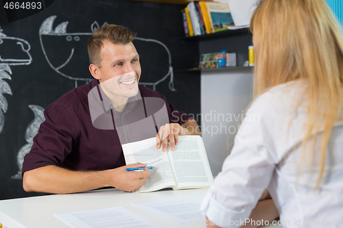 Image of Male teacher and female parent having a discussion in classroom. Mom at teacher parent meeting at kindergarten