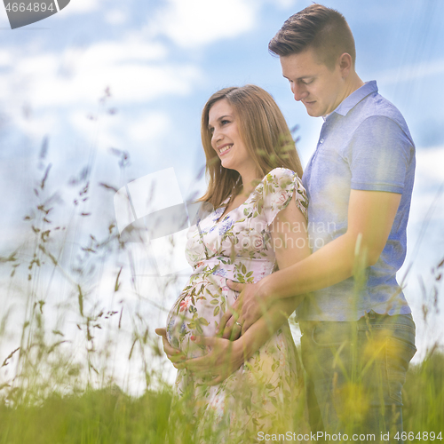 Image of Young happy pregnant couple hugging in nature.