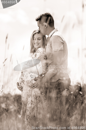 Image of Young happy pregnant couple hugging in nature.