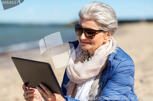Image of senior woman with tablet computer on beach