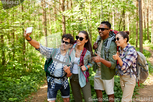 Image of friends with backpacks hiking and taking selfie