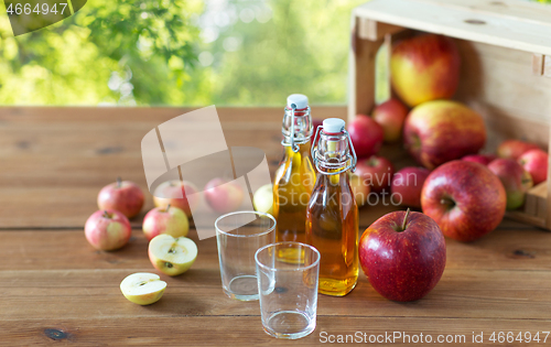 Image of glasses and bottles of apple juice on wooden table