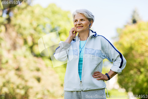 Image of senior woman with earphones at summer park