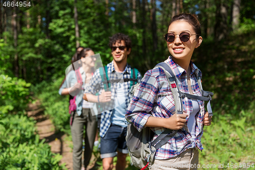 Image of group of friends with backpacks hiking in forest