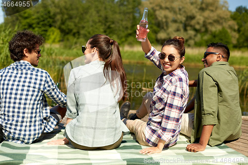 Image of happy friends with drinks on lake pier in summer