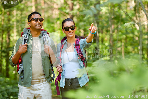 Image of mixed race couple with backpacks hiking in forest