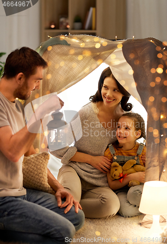 Image of happy family playing in kids tent at night at home