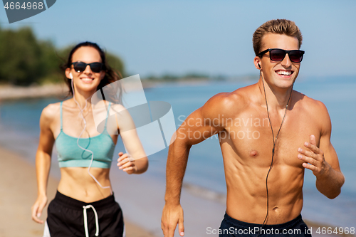 Image of couple with earphones running along on beach