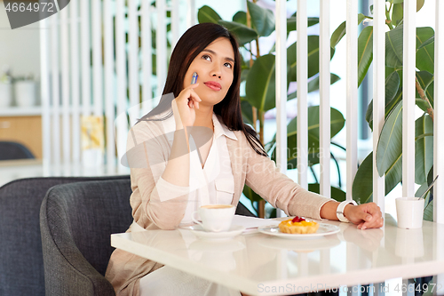 Image of asian woman with notebook and coffee at cafe