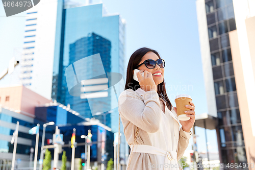 Image of smiling asian woman calling on smartphone in city