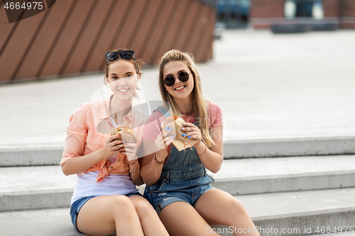 Image of teenage girls or friends eating burgers outdoors