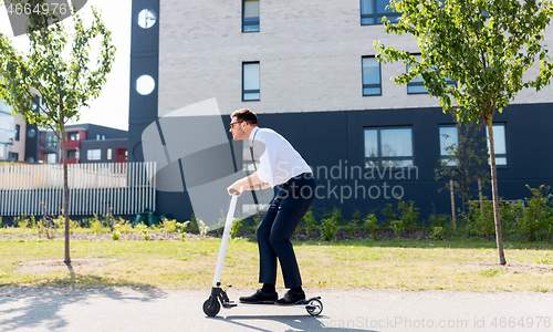 Image of young businessman riding electric scooter outdoors