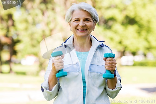 Image of senior woman with dumbbells exercising at park