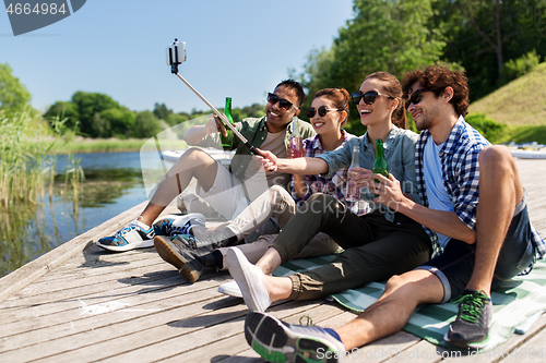 Image of friends with drinks taking selfie on lake pier