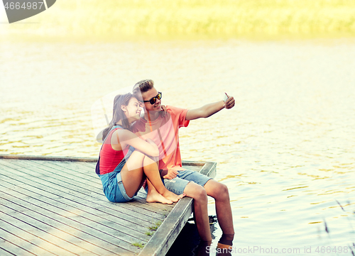 Image of happy teenage couple taking selfie on smartphone