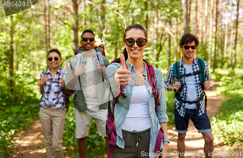 Image of friends with backpacks showing thumbs up in forest