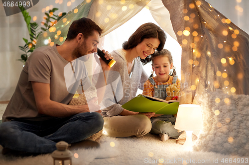 Image of happy family reading book in kids tent at home