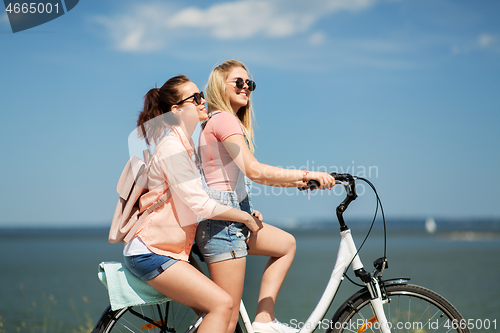 Image of teenage girls or friends riding bicycle in summer