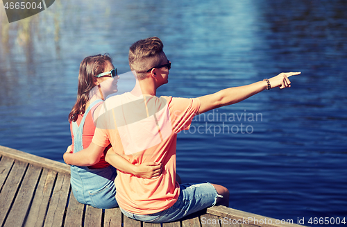 Image of happy couple pointing finger on summer river berth